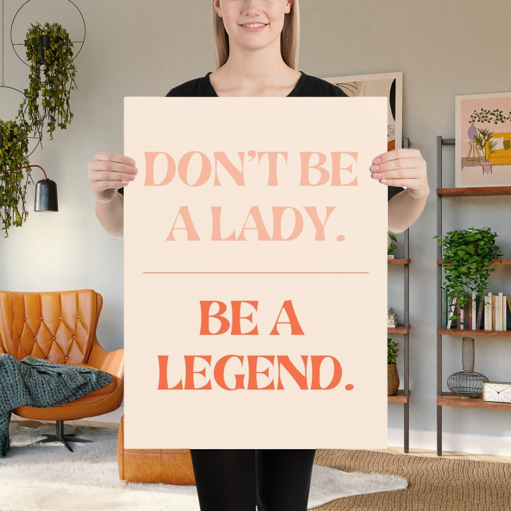 a woman holding a sign that says don't be a lady be a legend